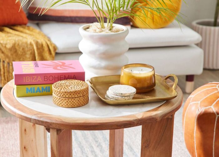 Decorating a coffee table in an elegant minimalist style with small vase with fresh flowers, a sleek candle, and a stack of your favorite coffee table books on the tray