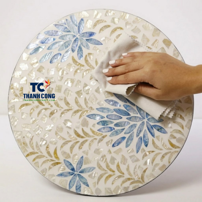 Artisan cleaning a handcrafted mother of pearl placemat featuring blue and white floral mosaic patterns for a high gloss finish
